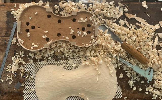 A violin in progress, covered with wood shavings.